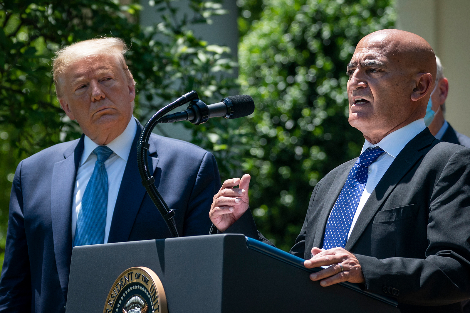 President Donald Trump listens as Moncef Slaoui, the head of the US government's effort to develop a vaccine against Covid-19, speaks about coronavirus vaccine development in the Rose Garden of the White House, in Washington, DC on May 15.