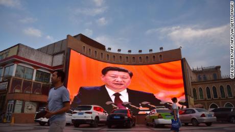 This photo taken on June 4, 2019, at the end of Ramadan, shows people walking past a screen showing images of Chinese President Xi Jinping in Kashgar, in China&#39;s western Xinjiang region. 