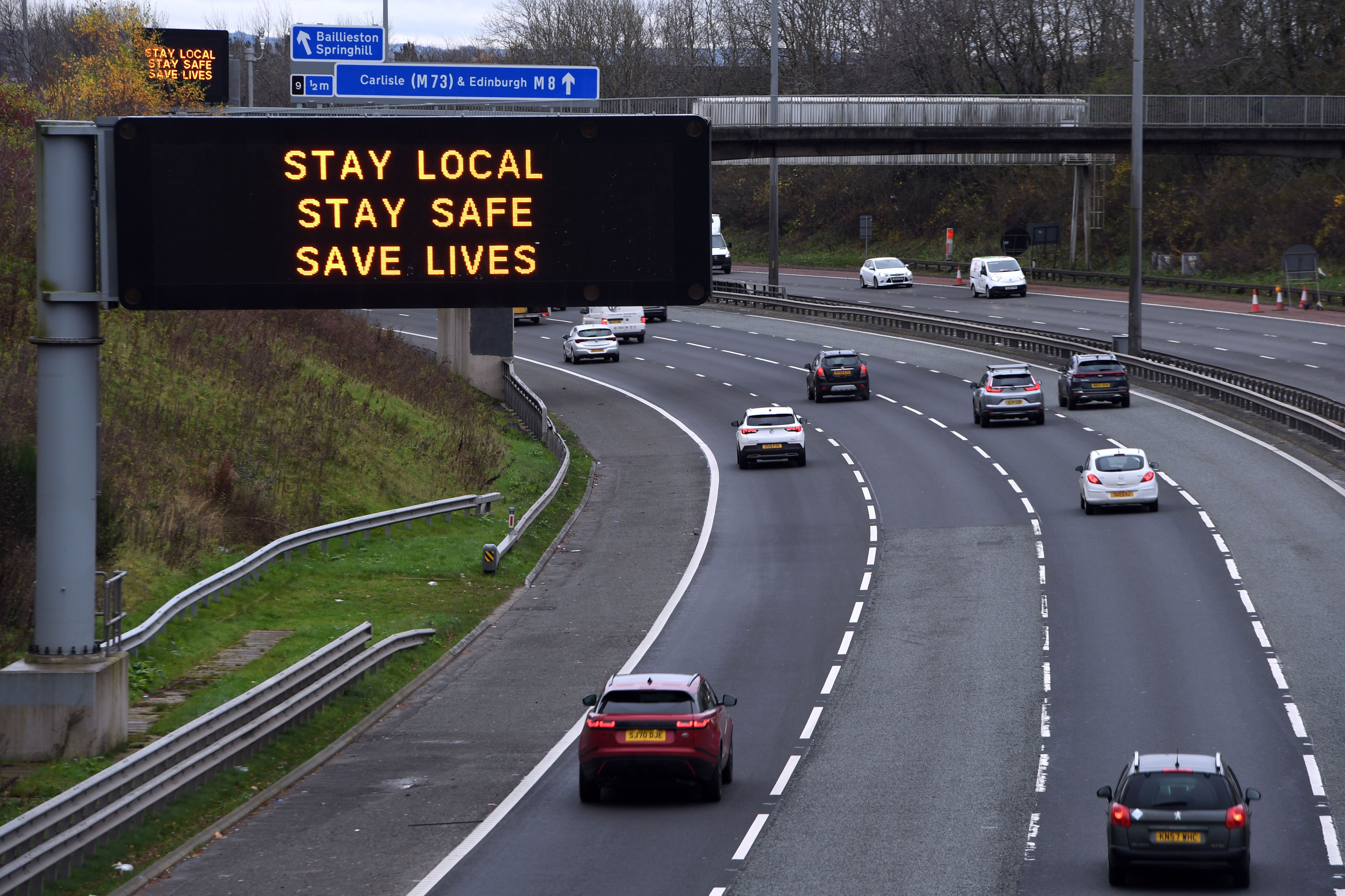 Cars pass a Covid warning sign on the eastbound M8 motorway in Glasgow ahead of the introduction of further coronavirus restrictions on Friday, November 20.