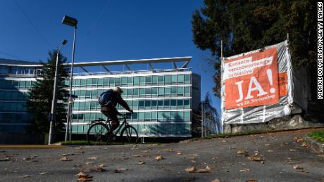 A man rides his bicycle next to the headquarters of Swiss food giant Nestlé and a campaign banner encouraging citizens to vote in favor of the Responsible Business Initiative.