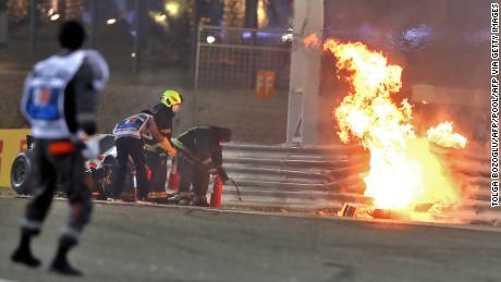 Race officials put out the fire on Grosjean&#39;s car at the Bahrain GP.