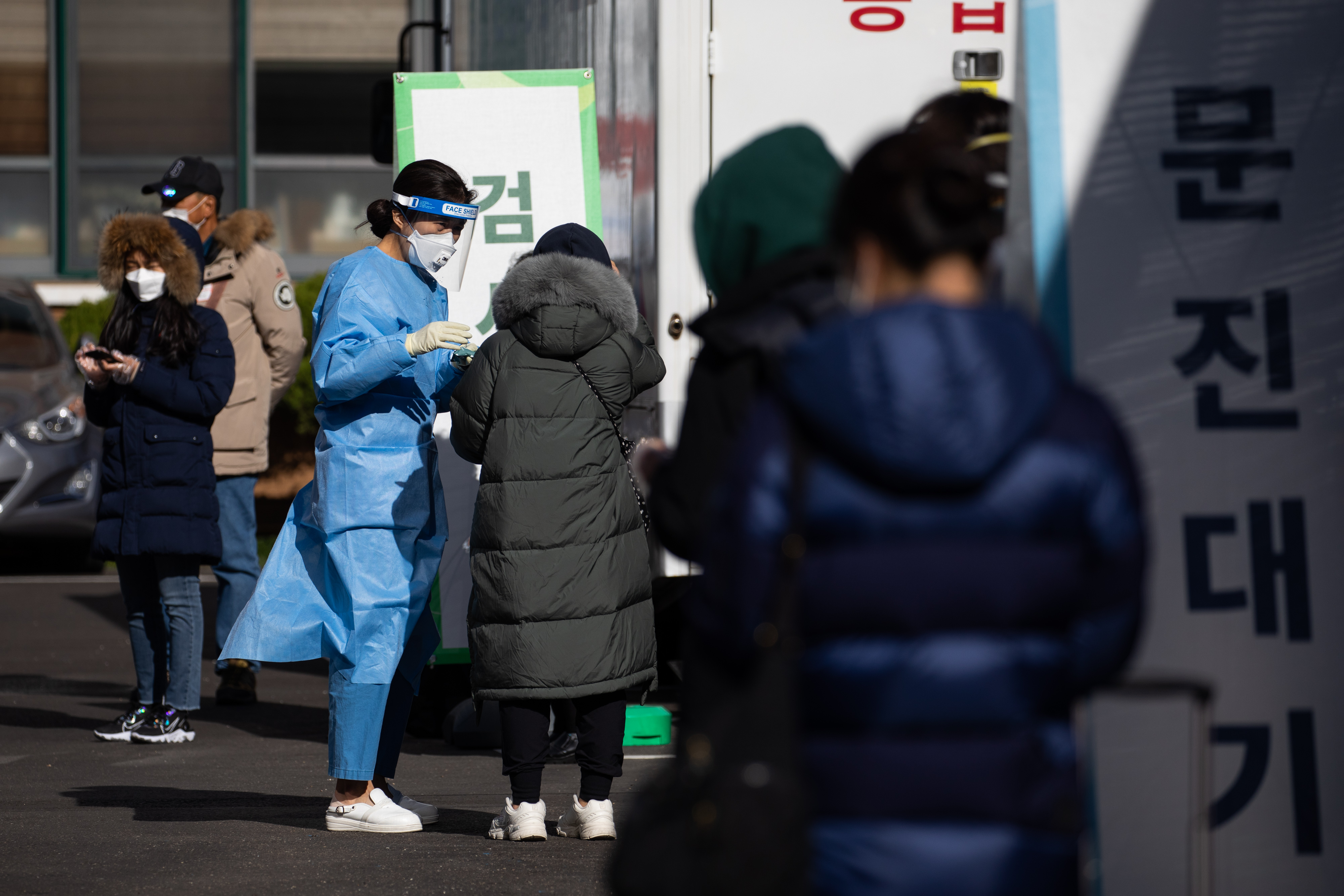 A medical worker talks to a person waiting in line at a Covid-19 testing station in Seoul, South Korea, on Saturday, November 28. 