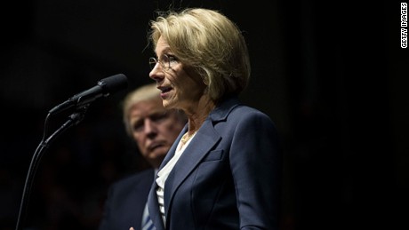 President-elect Donald Trump looks on as Betsy DeVos, his nominee for Secretary of Education, speaks at the DeltaPlex Arena, December 9, 2016 in Grand Rapids, Michigan. President-elect Donald Trump is continuing his victory tour across the country. (Drew Angerer/Getty Images)