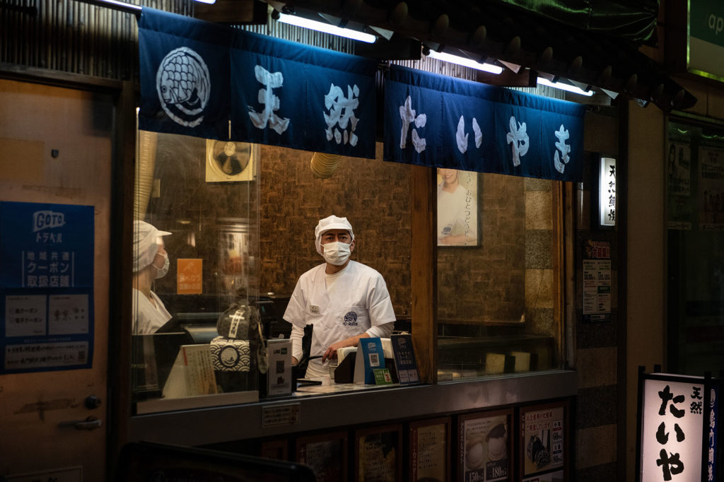  A chef wearing a face mask looks out from a restaurant window on December 23, in Tokyo, Japan.