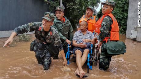 A resident is evacuated from a flooded street in Meishan in China&#39;s southwestern Sichuan province.