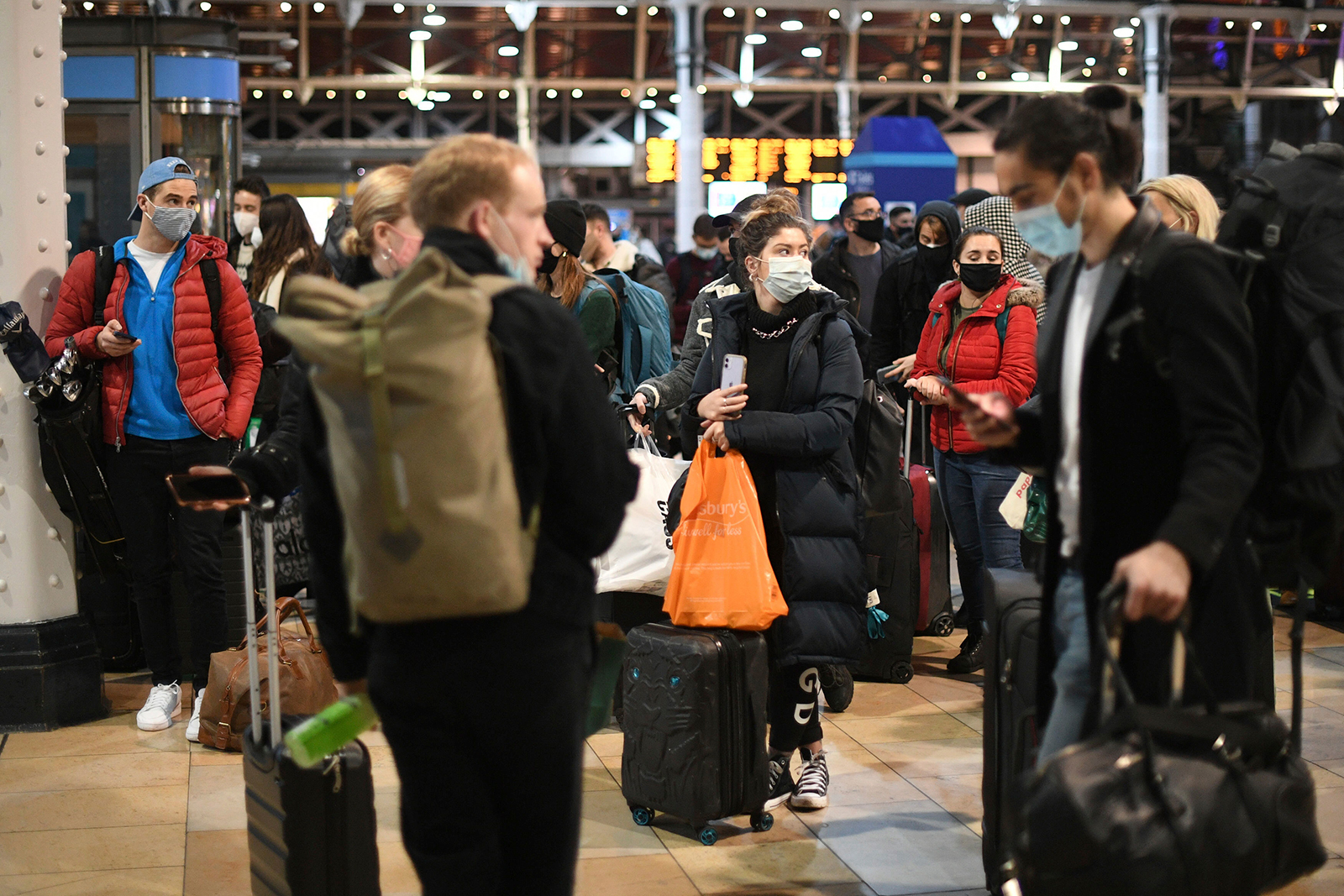 People wait on the concourse at Paddington Station in London on December 19 ahead of the introduction of tougher new restrictions.