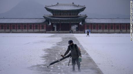 A worker uses a blower to clear snow from a courtyard at Gyeongbokgung palace in central Seoul on December 13, 2020.