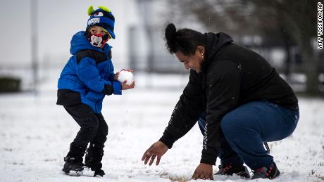 Jonathan Godoy, 5, looks for a target as Elias Gonzales makes a new snowball Sunday near Fort Worth.