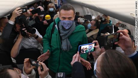 Passengers and journalists take photos of Alexey Navalny as he takes his seat on the flight Sunday.