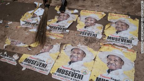 A worker sweeps the ground covered with campaign posters of President Yoweri Museveni on January 17, 2021 on a street in Kampala, Uganda.