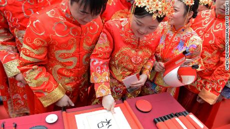 A couple marks fingerprints on ceremonial calligraphy during a traditional group wedding in Changsha, China.