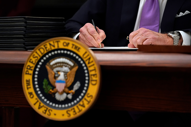 President Joe Biden signs executive orders after speaking about the coronavirus in the State Dinning Room of the White House, Thursday, Jan. 21, 2021, in Washington. 