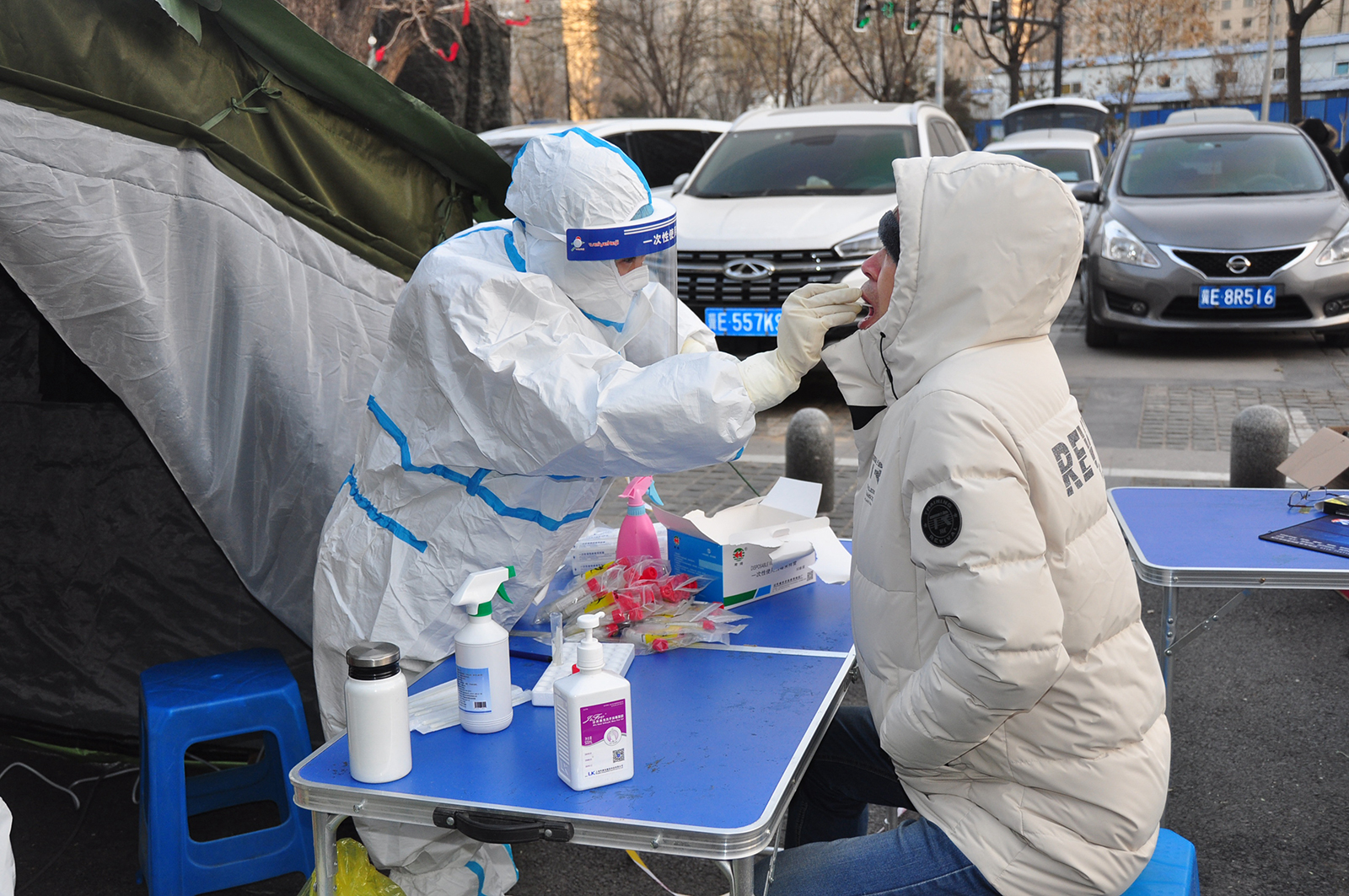 A medical worker wearing a protective suit collects a throat swab from a local resident for coronavirus (Covid-19) antigen rapid test at a temporary Covid-19 testing center in Xingtai, Hebei Province of China, on January 6.