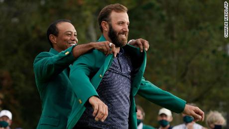 Tiger Woods helps Masters&#39; champion Johnson with his Green Jacket.