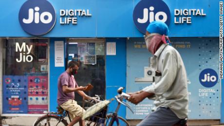 People on bicycle passes by a Jio store in Kolkata, India on July 13, 2020. 