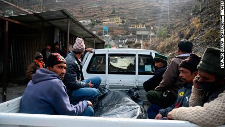 Relatives sit on the back a vehicle next to the body of a victim recovered from Raini village, outside a temporary morgue in Tapovan of Chamoli district on February 9, 2021.