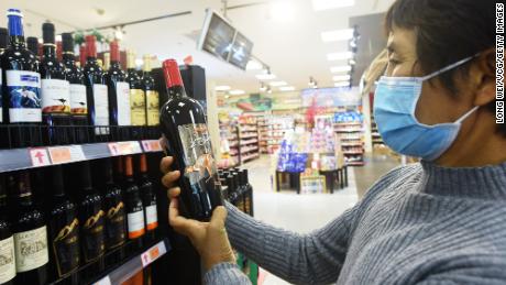 A customer looks at a bottle of wine imported from Australia at a supermarket on November 27 in Hangzhou, Zhejiang Province of China.