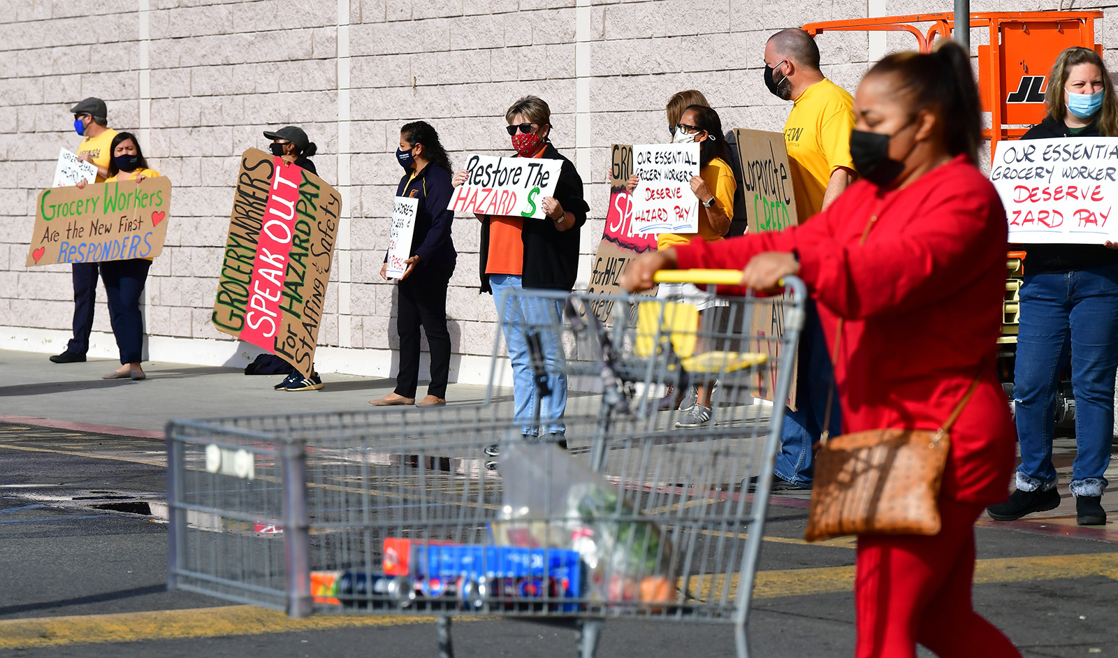 Workers hold placards in protest at a Food 4 Less supermarket in Long Beach, California on February 3, after a decision by owner Kroger to close two stores rather than pay workers an additional $4 in "hazard pay" for their continued work during the pandemic.