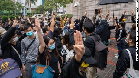 Pro-democracy activists gesture as they line up outside the West Kowloon court in support of the arrested activists.