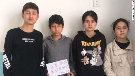 The four siblings -- Zumeryem, Yehya, Muhammad and Shehide -- hold up a sign saying, &quot;Mom, Dad, we miss you,&quot; from their state-run orphanage in Xinjiang in 2021.
