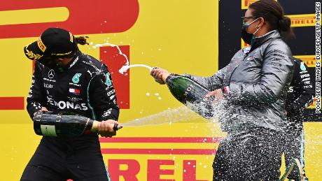 Lewis Hamilton and Stephanie Travers celebrate on the podium after the Styrian Grand Prix.
