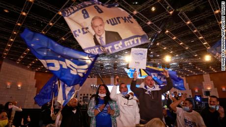 Likud supporters wave flags bearing the party name and the face of its leader, Benjamin Netanyahu, at its campaign headquarters in Jerusalem on March 23.