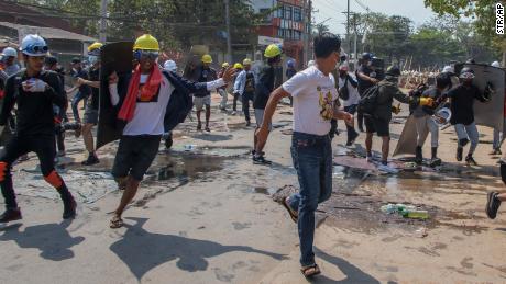 Anti-coup protesters retreat from the front lines after riot policemen fire sound-bombs and rubber bullets in Yangon, Myanmar, on March 11.
