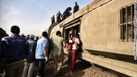 People inspect the damaged wagons of a passenger train, which went off the tracks near Toukh. 