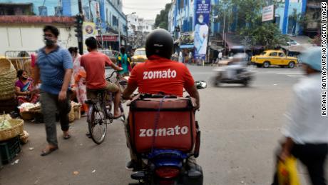 A Zomato delivery rider waits to cross a road in Kolkata, India. 