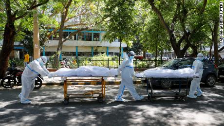Health workers wearing personal protective equipment  carry bodies of people who were suffering from Covid-19 outside the Guru Teg Bahadur hospital, in New Delhi, India, on April 24.