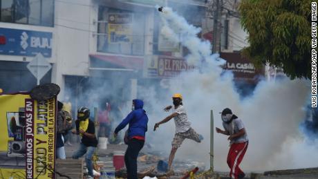 A demonstrator throws a tear gas canister at riot police officers in Cali, Colombia, on May 3, 2021. 