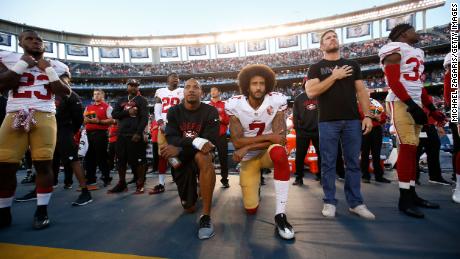 Eric Reid and Kaepernick kneel on the sideline during the national anthem.