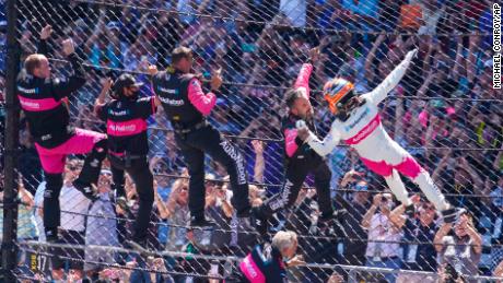 Helio Castroneves of Brazil celebrates with his team as he climbs the fence at the start/finish line after winning the Indianapolis 500 auto race at Indianapolis Motor Speedway in Indianapolis, Sunday, May 30, 2021.