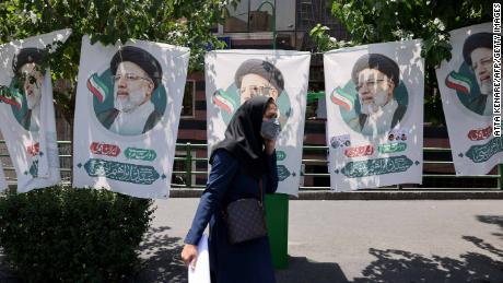 An Iranian woman walks past banners of ultraconservative cleric and presidential candidate Ebrahim Raisi, in Tehran, on June 17, 2021.