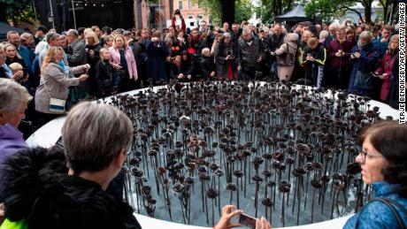 People stand next to the &quot;Iron roses&quot; memorial outside Oslo Cathedral on September 28, 2019, to commemorate the 77 victims of Anders Behring Breivik&#39;s attacks.